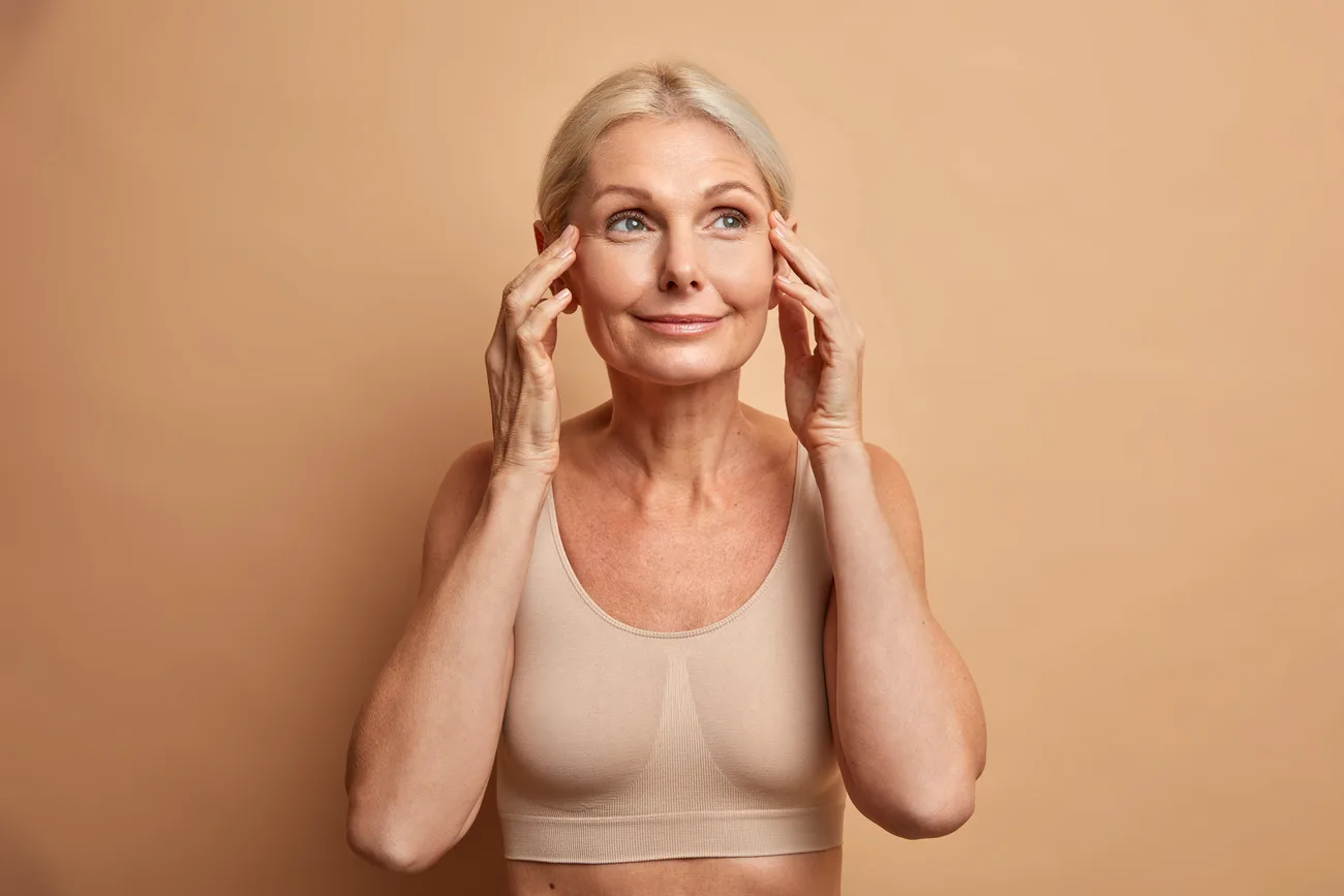 Femme observant sa peau avec attention dans la lumière douce du matin